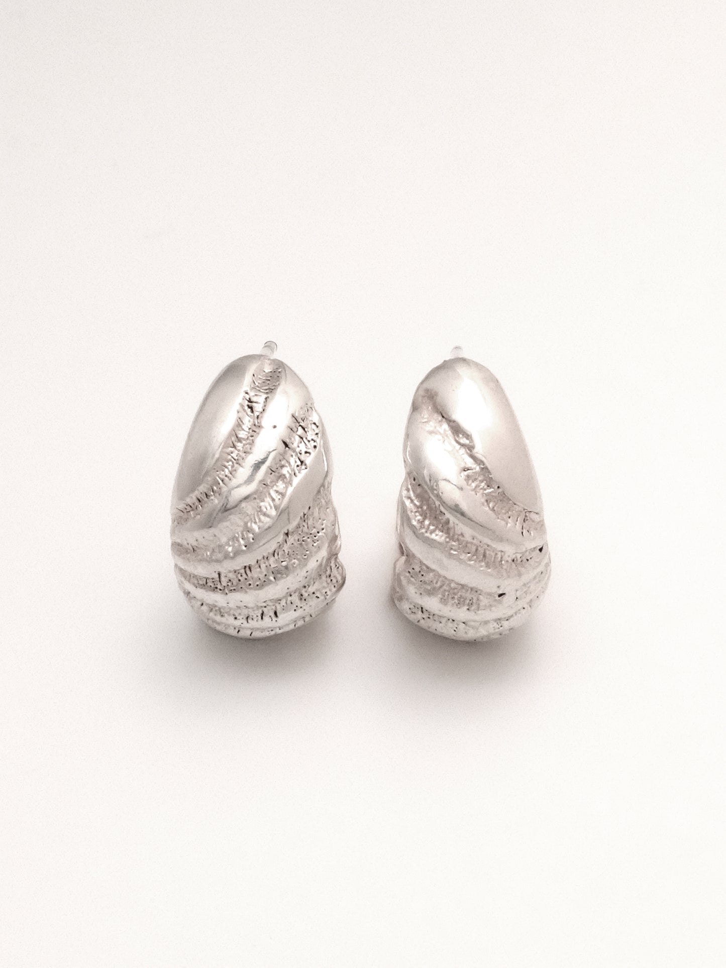 A close up of the same pair of Sterling Silver hoop earrings, positioned upright and side by side to show the radiating texture and subtle organic difference of the mirrored right and left.