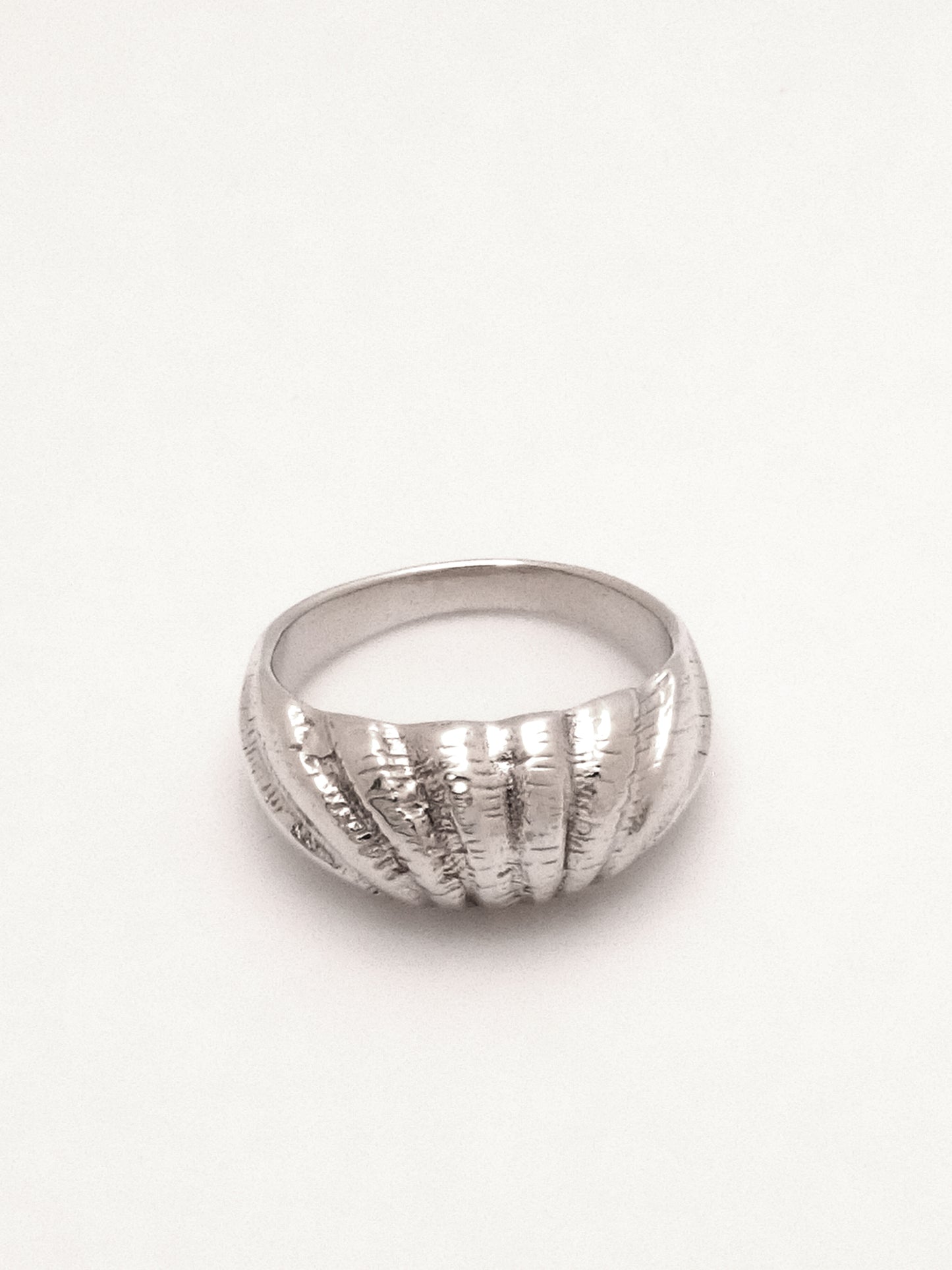 The same sterling silver dome profile ring with shell texture as the previous images captured lying flat with the top of the ring focal, capturing the outward endpoints of the shell like texture.