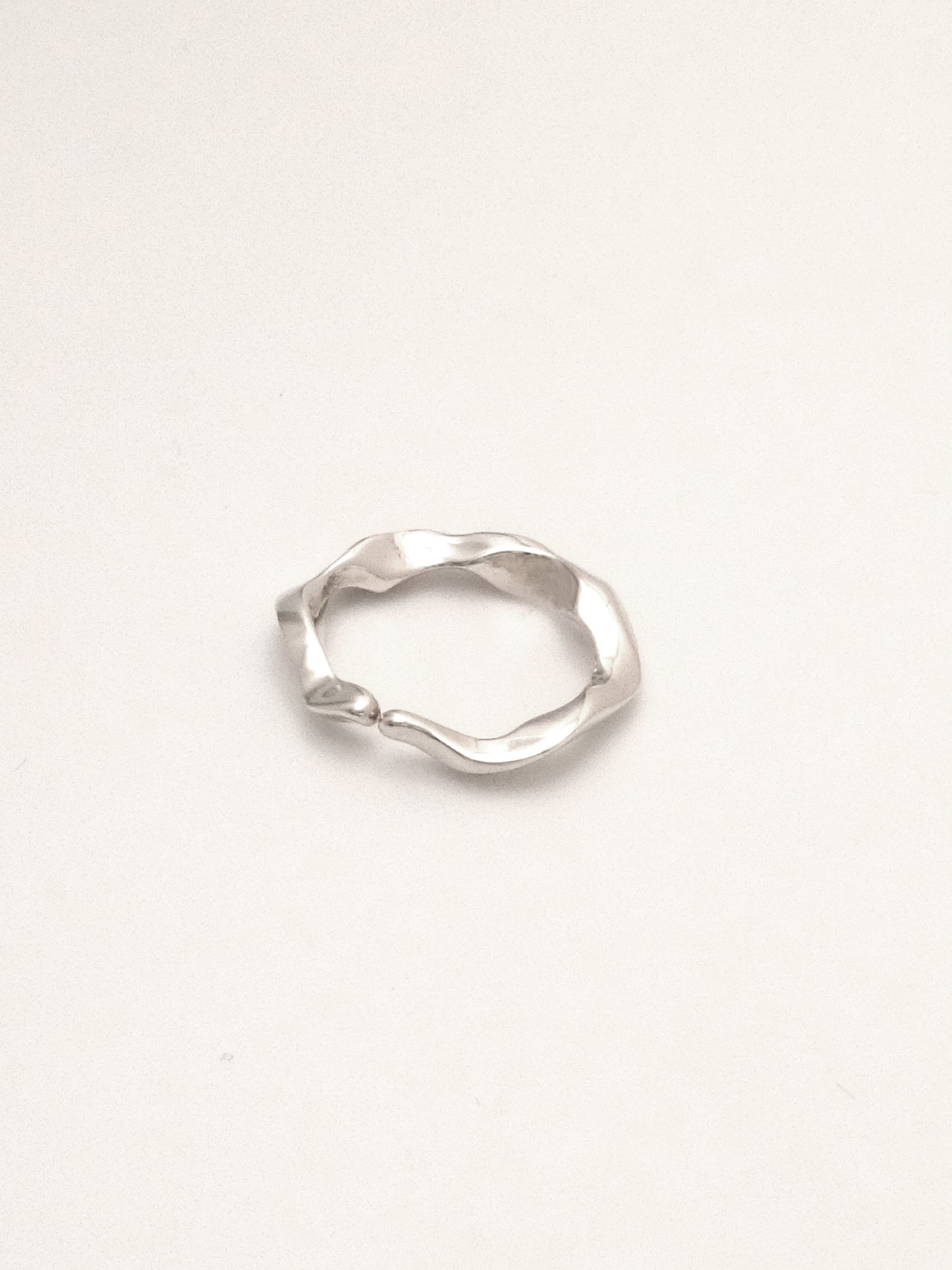 close up of sterling silver ring band with an undulating form with softly tapered  organic endpoints meeting at the center. 