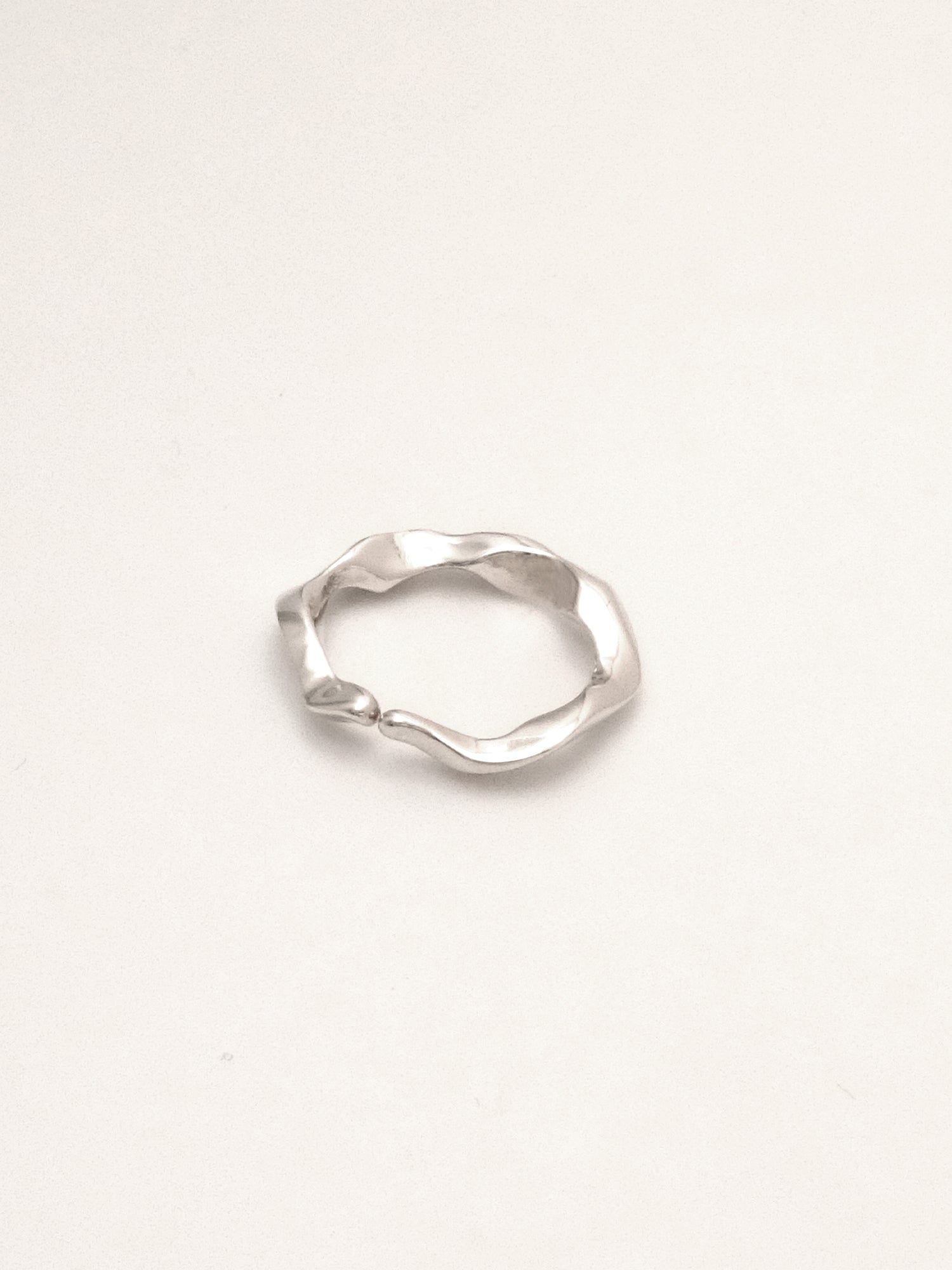 close up of sterling silver ring band with an undulating form with softly tapered  organic endpoints meeting at the center. 