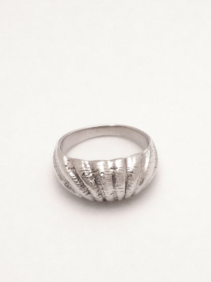 The same sterling silver dome profile ring with shell texture as the previous images captured lying flat with the top of the ring focal, capturing the outward endpoints of the shell like texture. 